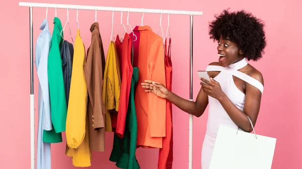 アフリカの女性のショッピング近くに立って服レール、ピンクの背景 — ストック写真