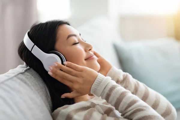 Fin de semana Relájate. Hermosa mujer asiática en auriculares inalámbricos escuchando música en casa —  Fotos de Stock