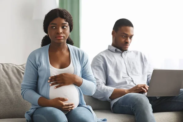 Mujer africana embarazada solitaria sentada junto a su marido usando una computadora portátil — Foto de Stock