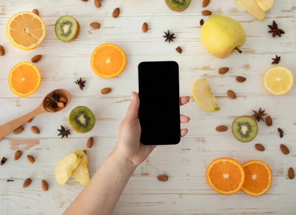 Dieting concept. Woman holding smartphone with blank screen, mockup for your advertisement, top view — Stock Photo, Image