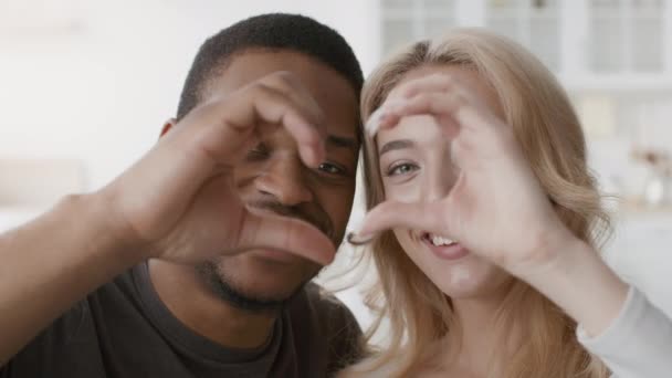 Vielseitiges Paar zeigt Herz-Geste und lächelt in die Kamera — Stockvideo