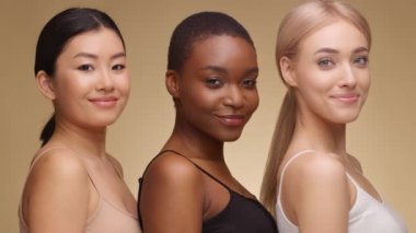 Çeşitli güzellikler. Üç mutlu çoklu etnik kadının profil portresi. Kameraya bakıp birlikte gülümsüyorlar.