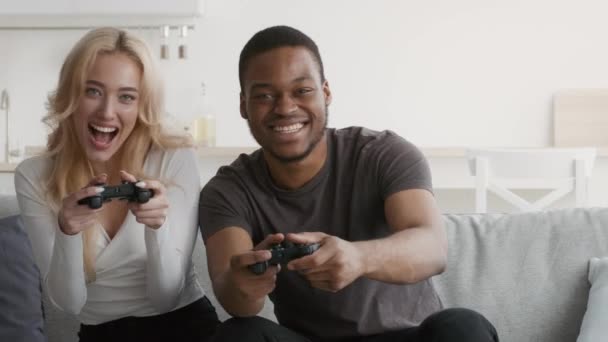 Multi-etnische paar spelen video game zitten op de bank thuis — Stockvideo