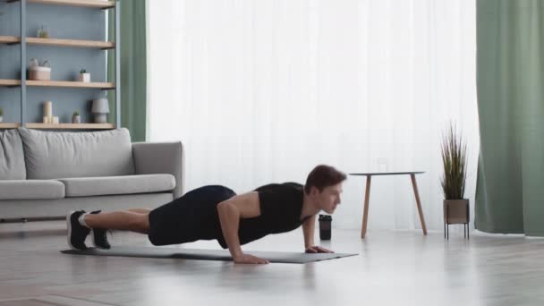 Joven chico fuerte practicando flexiones de ejercicio en casa, ejercitando flexiones de entrenamiento en el suelo, cámara lenta — Vídeos de Stock