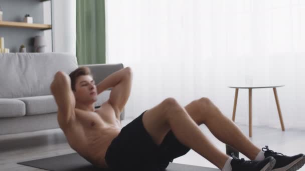 Junger muskulöser Darm mit nacktem Oberkörper praktiziert Crunches-Übungen zu Hause, macht Bauchmuskeltraining für sportlichen Bauch — Stockvideo