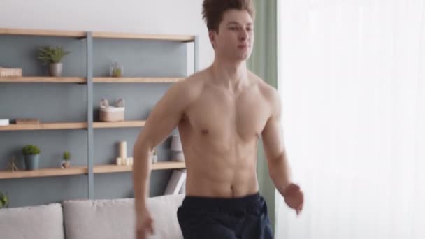 Close up portrait of active man sprinter running on place, exercising at home with naked muscular torso, tracking shot — Stock Video