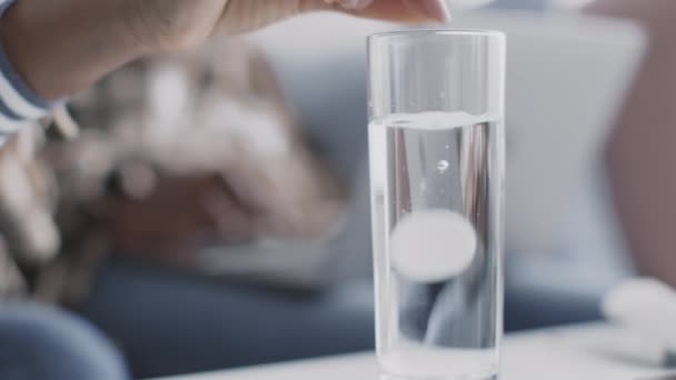 Primer plano de la mano femenina negra poniendo aspirina píldora soluble en un vaso de agua y dándoselo al hombre enfermo, cámara lenta — Vídeos de Stock