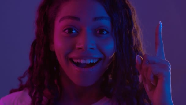 Creative thinking. Young african american lady pointing finger up and smiling, having great idea, posing in neon lights — Stock Video