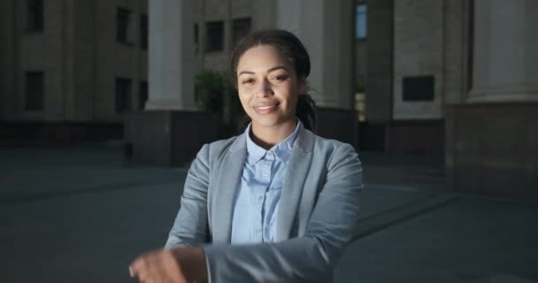 Självsäker afrikansk amerikansk kvinnlig chef i formell kostym poserar på kontoret byggnad med vikta händer, ler mot kameran — Stockvideo