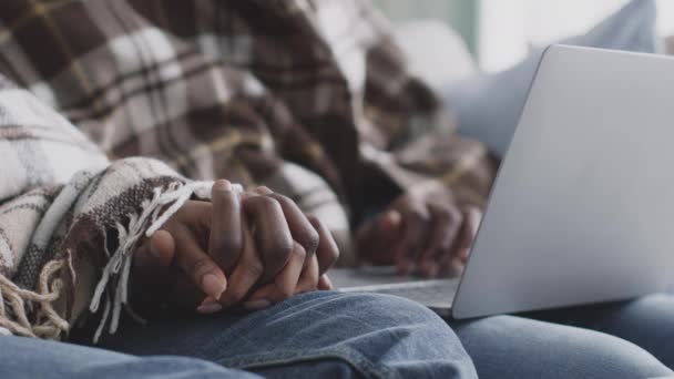 Närbild bild bild av oigenkännliga afrikanska amerikanska par hålla händer, sitter tillsammans på soffan och bläddrar på laptop — Stockvideo