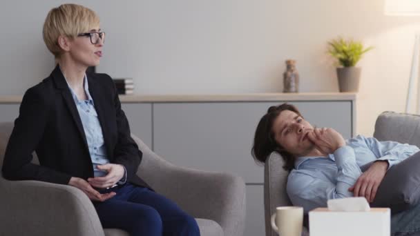 Homem deprimido deitado no sofá, psicólogo profissional conversando com o cliente, analisando problemas e dando conselhos — Vídeo de Stock