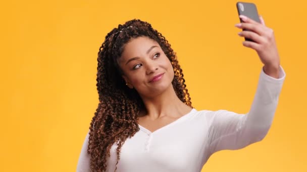 Joven mujer afroamericana segura de sí misma haciendo foto selfie en el teléfono inteligente, sonriendo y posando para la cámara gadget — Vídeos de Stock