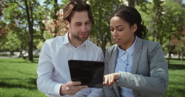 Diversos socios comerciales hombre y mujer que trabajan juntos al aire libre, mirando la tableta digital y discutiendo el proyecto — Vídeo de stock