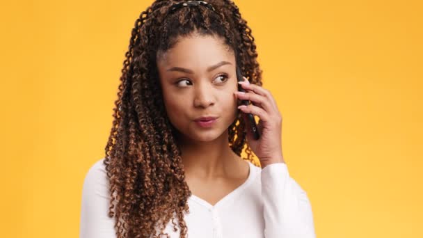 Estudio de alegre joven afroamericana con peinado afro hablando con amigos a través del teléfono celular y sonriendo — Vídeo de stock