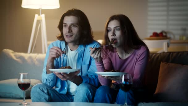 Noite de família acolhedora. Bonito casal apaixonado jantando juntos e assistindo tv em casa, discutindo show — Vídeo de Stock