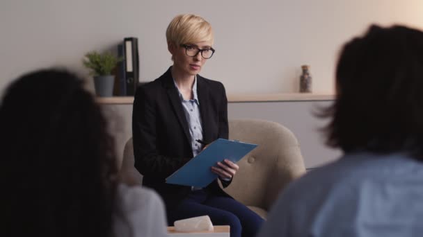 Confident middle aged woman family advisor listening to married couple with relationships problems and taking notes — Video