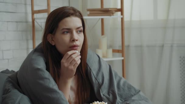 Apathische Dame isst Popcorn in Decke gewickelt im Schlafzimmer — Stockvideo