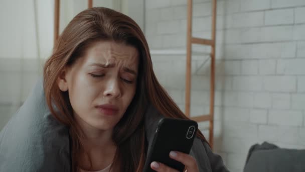Zdesperowana młoda dama płacze patrząc na komórkę w sypialni — Wideo stockowe