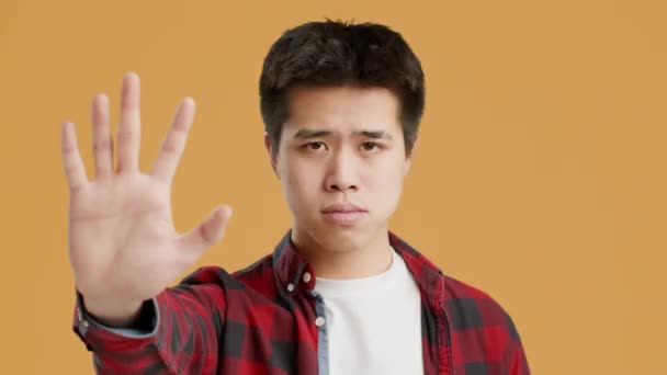 Asiático chico gestos parada a cámara sacudiendo cabeza, naranja fondo — Vídeos de Stock