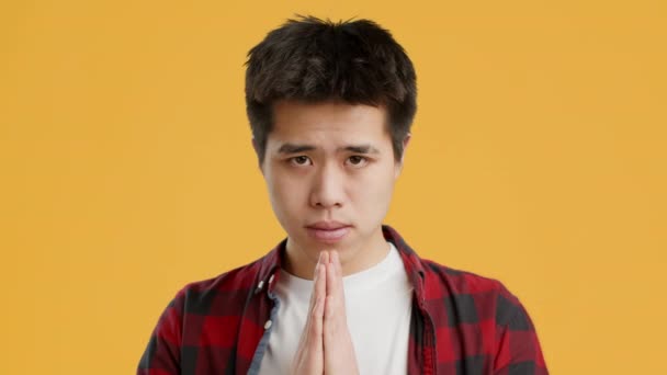 Ázsiai Guy imádkozó összecsukható kezek imában gesztus, sárga háttér — Stock videók