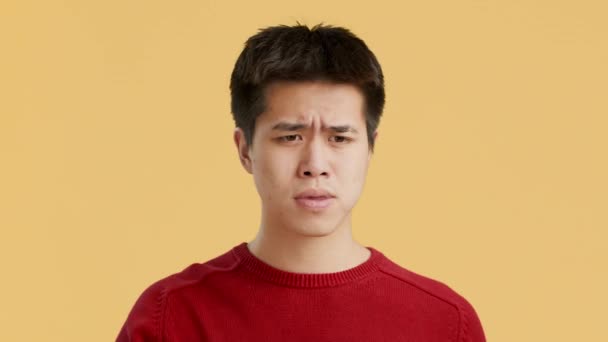Asiatisk man tar av glasögon och gnugga Nosebridge, Orange bakgrund — Stockvideo