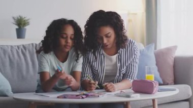 Neşeli Afro-Amerikan anne ve kızı evde resim çiziyor, birlikte mutlu hafta sonları geçiriyorlar.