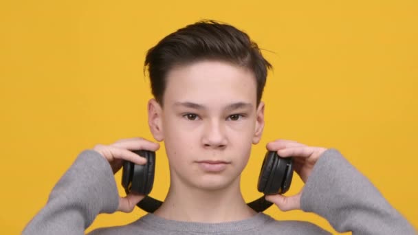 十代の男の子は音楽を聞いてヘッドフォンを身に着けています,スタジオショット — ストック動画