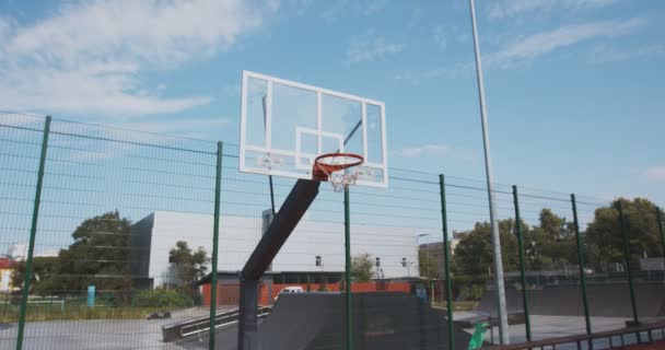 Забиваю гол. Баскетболист Мбаппе бросил мяч в обруч на открытой площадке для стритбола — стоковое видео