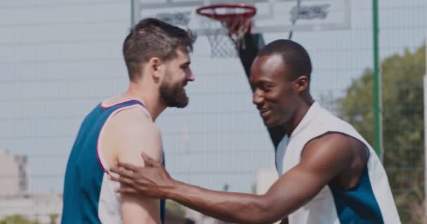 Deporte y amistad. Amigos multiétnicos jugadores de baloncesto saludándose en la cancha de streetball al aire libre — Vídeos de Stock