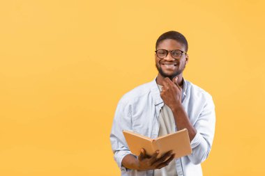 Öğrenme konsepti. Mutlu Afrikalı genç Amerikalı çocuk eğitim için kitap okuyor sarı arka plan ve boş alan