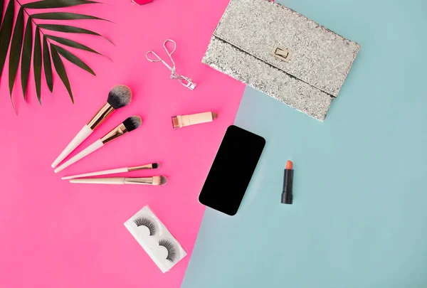 Красота блоггер рабочее пространство, телефон с Blank экраном для вашего дополнения или приложения, косметические средства на розовом и голубом фоне — стоковое фото