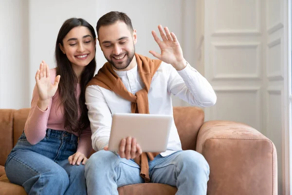 Pareja árabe haciendo videollamada vía tableta digital en casa —  Fotos de Stock