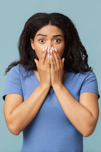 Omg. Mujer negra impactada cubriéndose la boca con palmas de las manos y mirando a la cámara sobre fondo azul —  Fotos de Stock