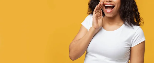 A partilhar notícias. Senhora negra irreconhecível contando algo secreto sobre o fundo do estúdio amarelo, panorama — Fotografia de Stock