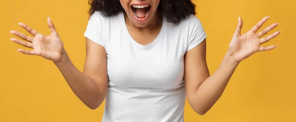 Chocada mulher negra irreconhecível gritando e estendendo as mãos em descrença no fundo do estúdio amarelo, panorama — Fotografia de Stock
