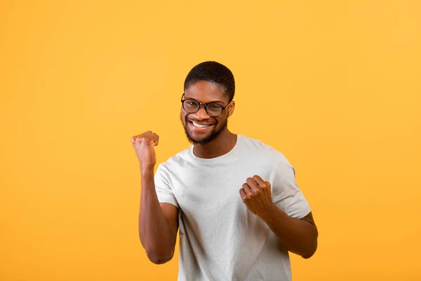 Succes, overwinning en geluk concept. Overblij zwarte man uiten emoties van overwinning en succes, gele achtergrond — Stockfoto