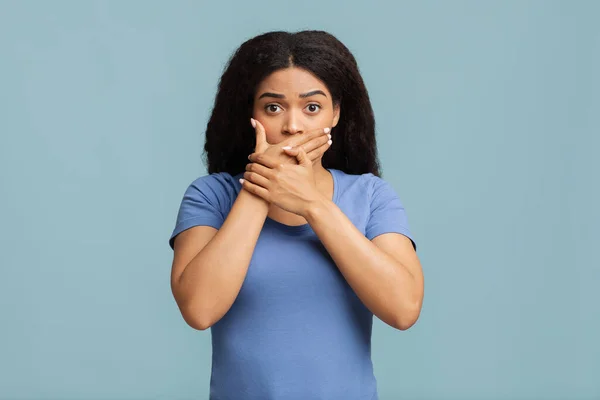 Opa. Africano americano mulher cobrindo sua boca com as duas mãos e olhando para a câmera contra o fundo do estúdio azul. — Fotografia de Stock