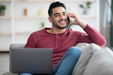 Olumlu Arap adam evde telefon görüşmesi yapıyor.