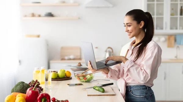 샐러드를 요리하고 노트북 과 주방을 사용하는 여자 — 스톡 사진
