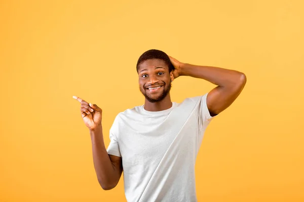 Advertentiebanner. Jonge zwarte man wijzend vinger opzij reclame uw tekst of logo op gele achtergrond — Stockfoto