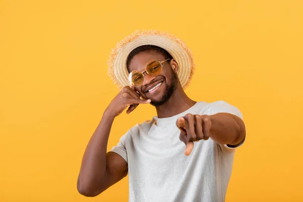 Glada svart kille i trendiga sommar outfit visar kallar mig gest, ler mot kameran på gul studio bakgrund — Stockfoto