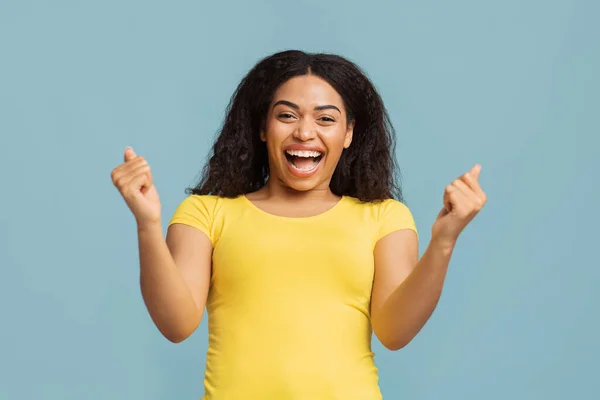 Alegria da vitória. Emocional afro-americana senhora torcendo e gritando, celebrando a vitória sobre o fundo azul — Fotografia de Stock