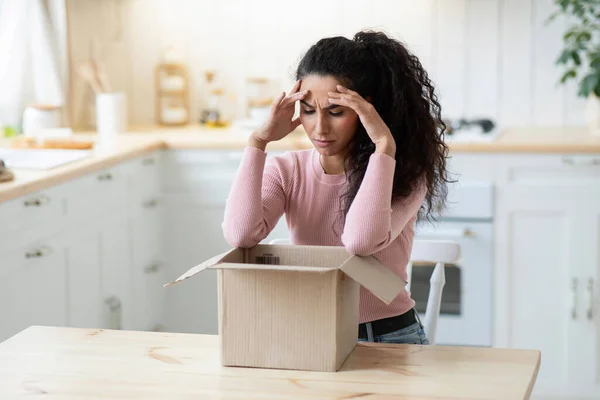 Objeto equivocado. Mujer joven frustrada mirando el paquete abierto con desesperación — Foto de Stock