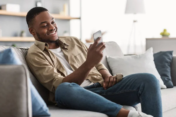 Zijaanzicht van Afro-Amerikaanse man met behulp van smartphone thuis — Stockfoto