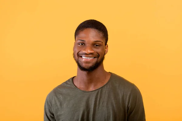 Ritratto maschile. Positivo uomo afro-americano guardando e sorridendo alla fotocamera isolata su sfondo giallo — Foto Stock