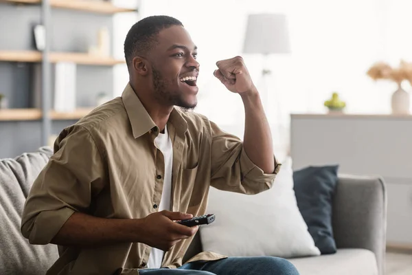 Tipo negro emocional viendo deportes en la televisión en casa, Vista lateral — Foto de Stock