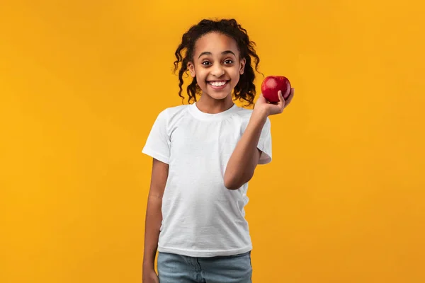 Πορτρέτο ενός χαρούμενου μαύρου κοριτσιού που κρατά κόκκινο μήλο — Φωτογραφία Αρχείου