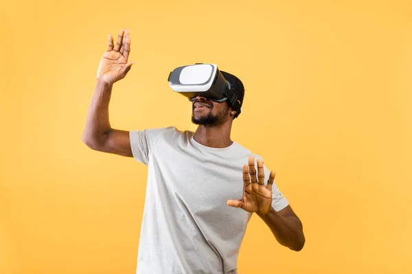 Tecnologia incredibile e mondo virtuale nella simulazione 3D. afroamericano uomo in vr occhiali su sfondo giallo — Foto Stock