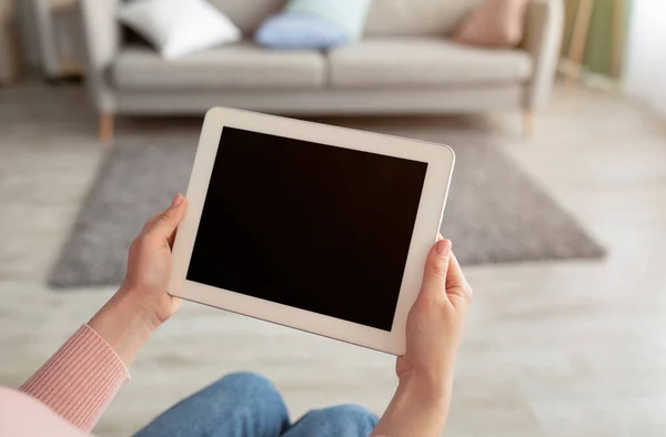 Donna che tiene tablet computer con schermo vuoto per la pubblicità app, seduto a casa in salotto interno — Foto Stock