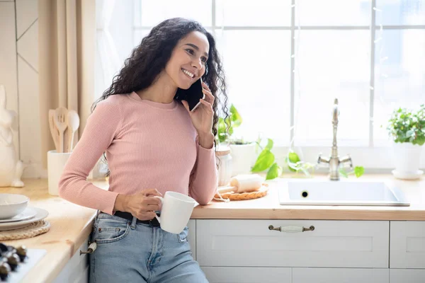 Glada Brunett Lady talar på mobiltelefon och dricka kaffe i köket — Stockfoto